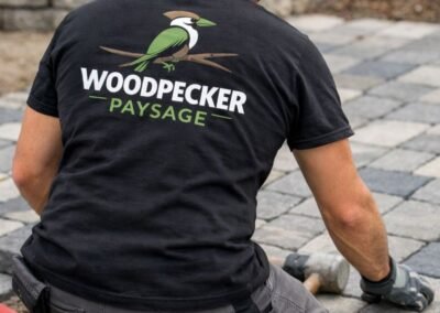 Poseur de pavés portant un tee-shirt Woodpecker Paysage avec logo pendant la création d’une allée pavée à Saint-Augustin 77515